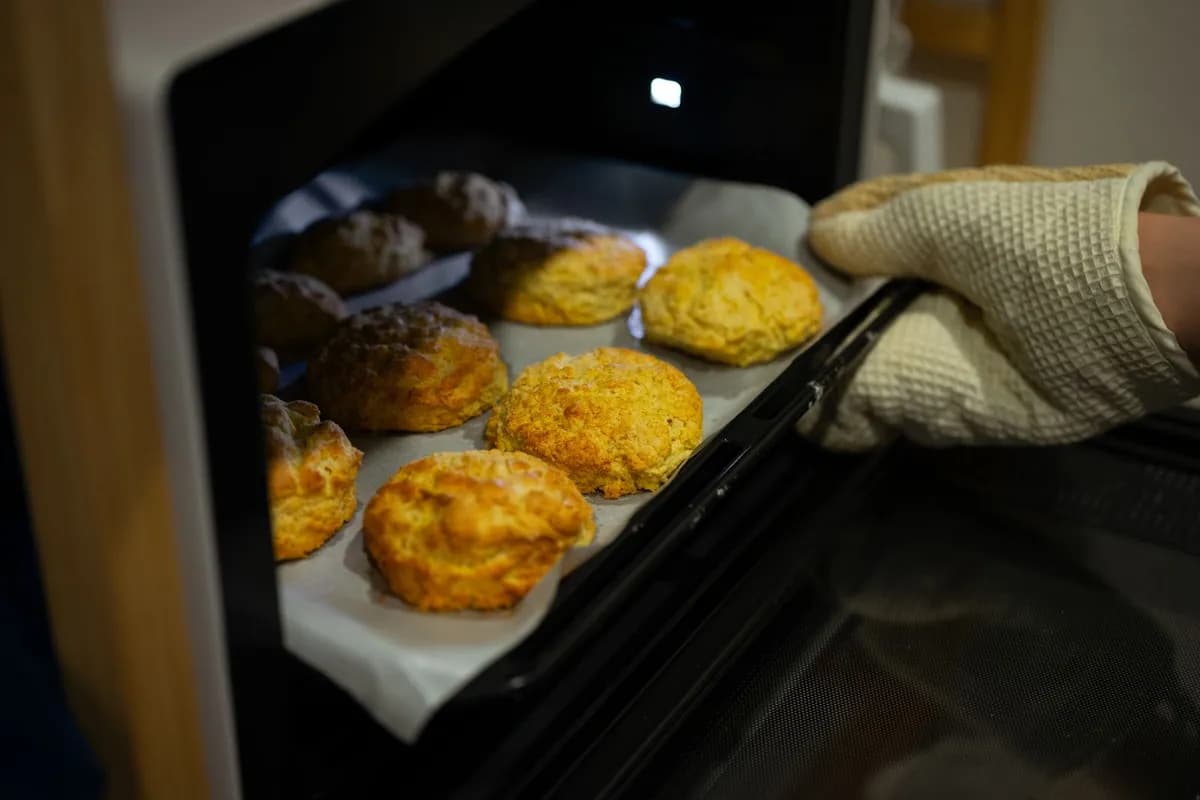 Tray of fresh biscuits being taken out of a home oven